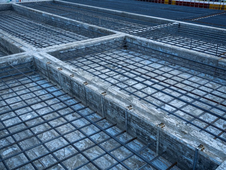 Orthographic high-resolution view of a reinforced concrete foundation with detailed steel rebar grids, cool blue and slate tones, overcast daylight, sharp structural geometry, 35mm