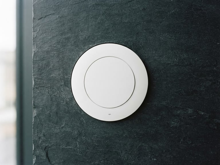 Sleek white circular access point mounted on a dark slate wall, clean architectural lighting, sharp focus, technical minimalism, 35mm