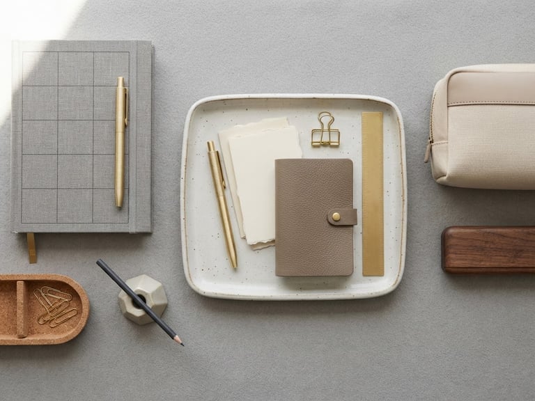A clean, minimalist flat-lay of premium organization tools on a soft grey surface, bright diffused natural light, sharp focus on tactile textures