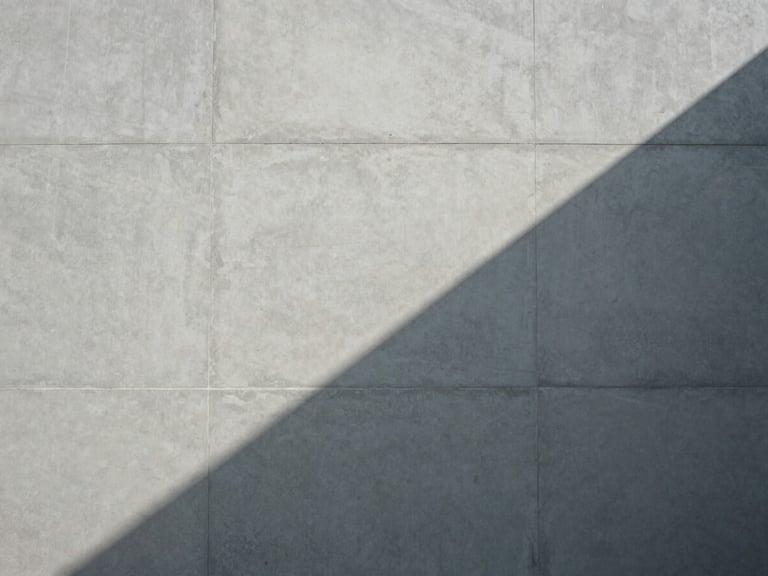 Abstract geometric pattern of light and shadow on a concrete wall, sharp lines, desaturated.
