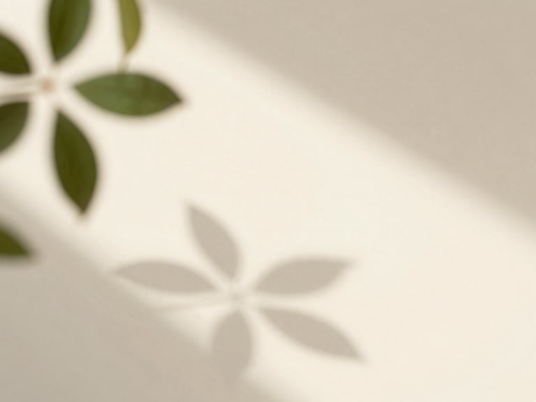 Soft morning light filtering through green leaves, casting organic shadows on a warm cream surface, clean minimalist setting