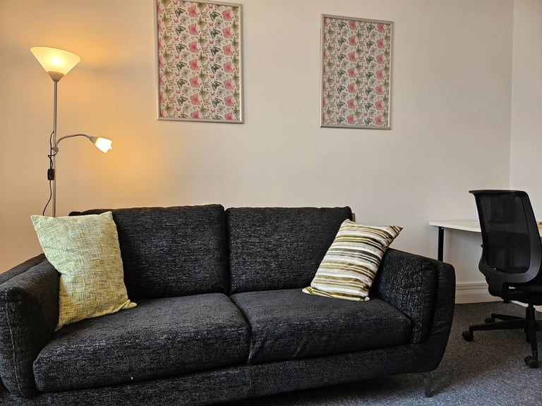 Modern counselling room featuring a charcoal gray fabric sofa with decorative pillows