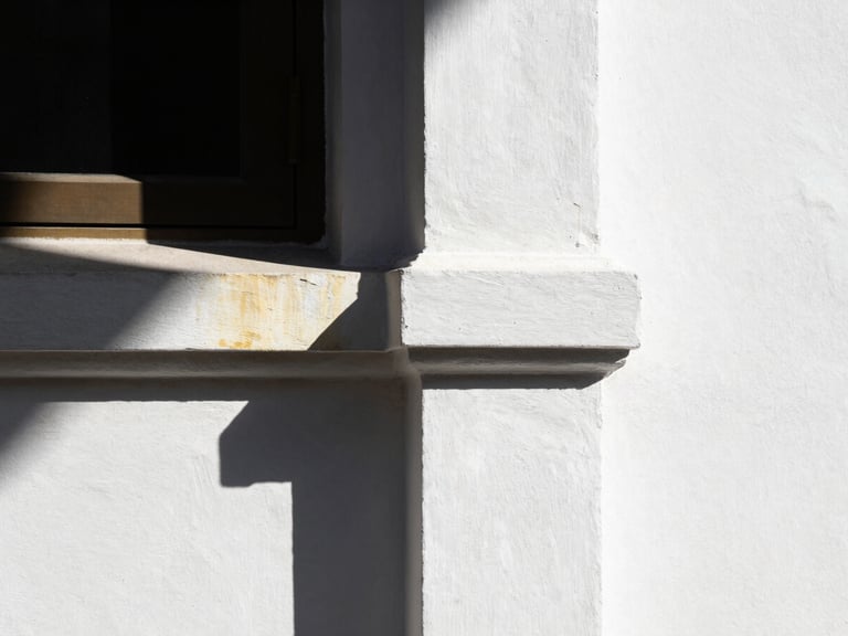 Sunlight hitting a perfectly smooth white painted wall, sharp corner detail, high-contrast architectural photography with subtle gold reflection