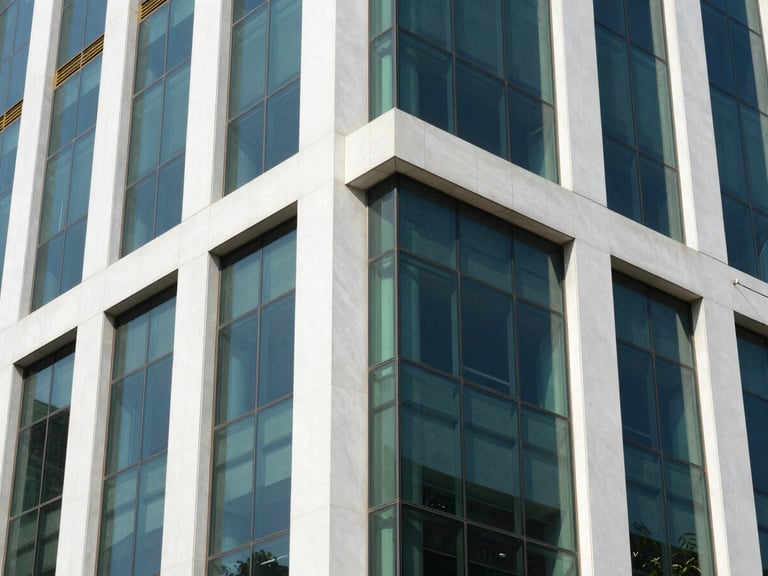 Sleek architectural detail of a modern glass and steel office building in Lahore, bright daylight, reflections of blue sky, 35mm lens.