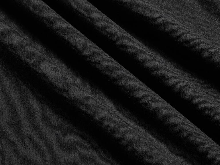 Extreme close-up of thick, tightly woven black cotton fabric texture, harsh studio key light, deep shadows, monochrome black and white, 35mm film