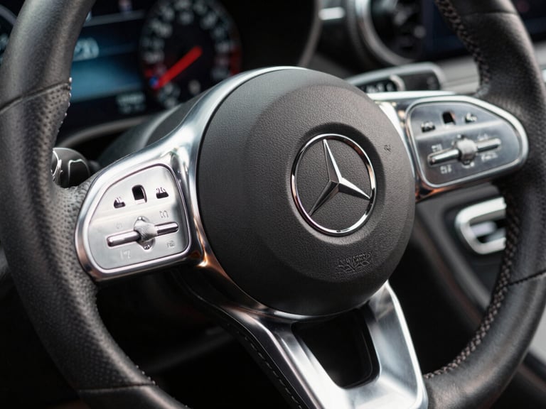 Extreme close-up of a high-performance Mercedes steering wheel, brushed platinum and hand-stitched charcoal leather, cold studio lighting, razor-sharp focus