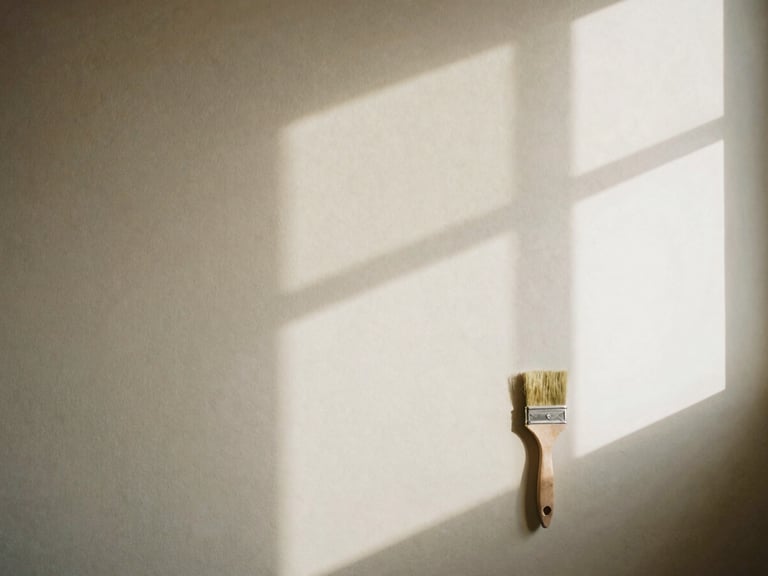 A freshly painted wall in a warm, neutral color, with soft shadows from a window, a painter's clean brush resting nearby, cozy domestic interior.