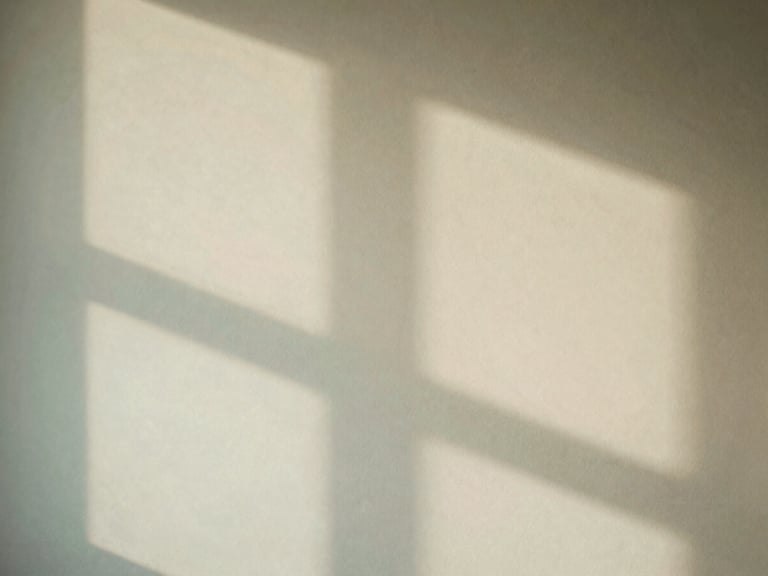 Abstract image of soft shadows on a beige textured wall, creating a calming and contemplative atmosphere, warm editorial photography, soft diffused window light, muted mint and beige tones, shallow depth of field, 35mm