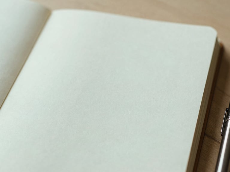 Delicate, abstract detail of a notebook with a pen, open to a blank page, suggesting reflection and new beginnings, warm editorial photography, soft diffused window light, muted mint and beige tones, shallow depth of field, 35mm