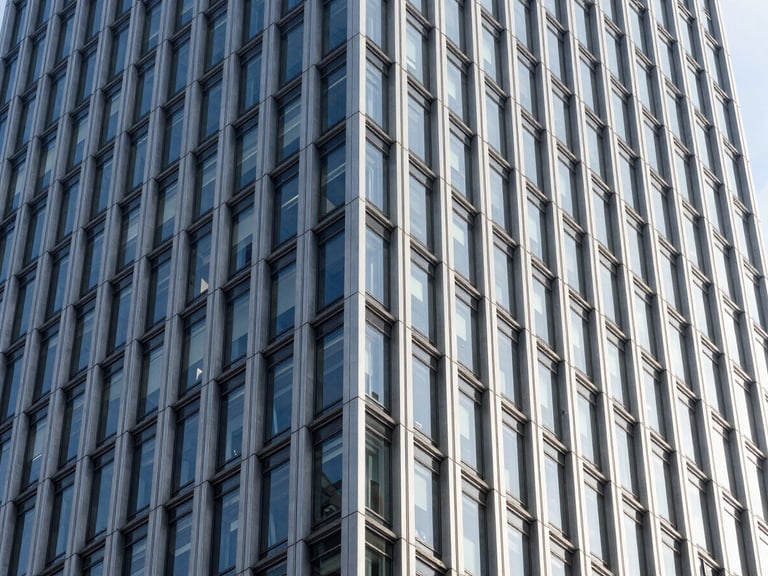 Architectural crop of a modern corporate skyscraper facade, sharp geometric steel and glass lines, crisp daylight, high contrast
