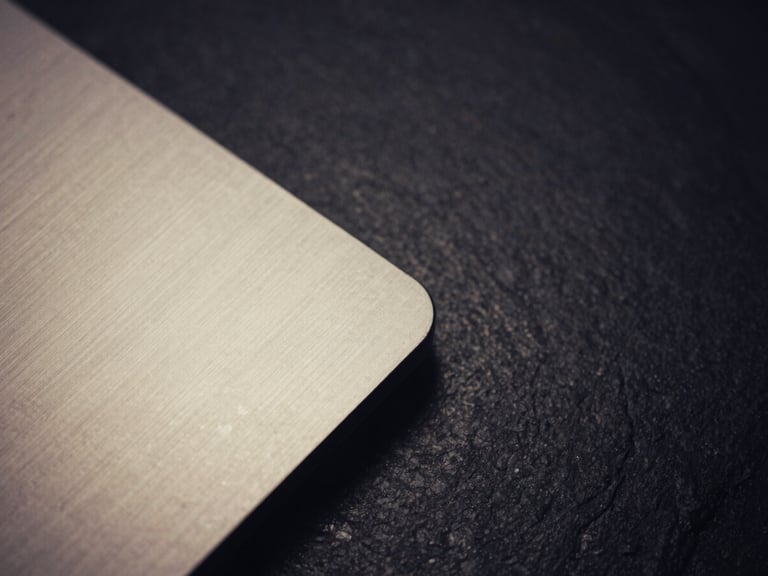 Macro close-up of brushed titanium and dark slate workspace, dramatic low-key chiaroscuro lighting, 35mm film aesthetic