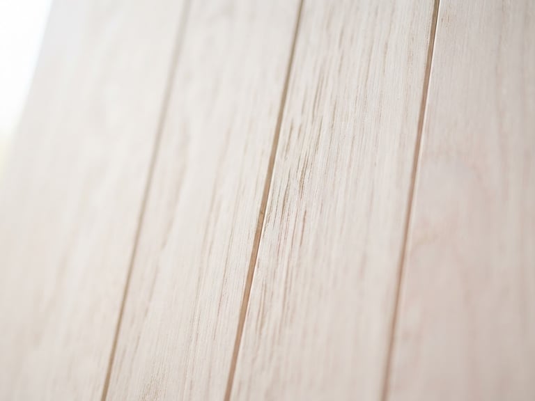Close-up of light-toned pastel wood grain with soft, diffused morning light, shallow depth of field, clean vertical lines.
