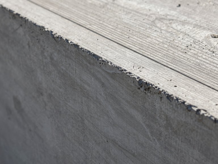 Extreme close-up of raw board-formed concrete texture, showing the grain of the wood panels imprinted on the cured gray surface, sharp morning light casting deep ridges.