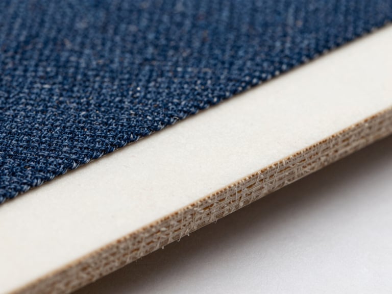 Extreme close-up macro shot of composite material edge showing embedded denim-fiber matrix, crisp directional studio lighting, sharp focus, 35mm