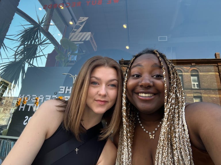 Two girls sitting in front of a store window