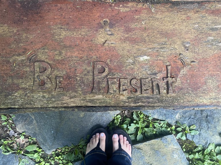 words "Be present" carved into wood