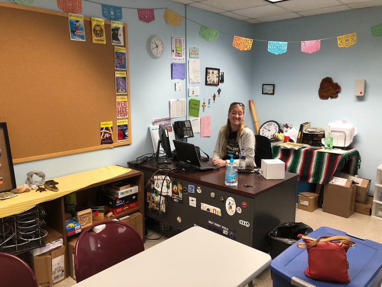 a teacher sitting at a desk in a classroom