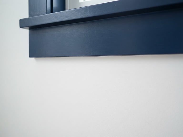 Close-up of a perfectly painted, crisp white wall meeting a deep navy trim, sharp line, natural coastal daylight, architectural detail.