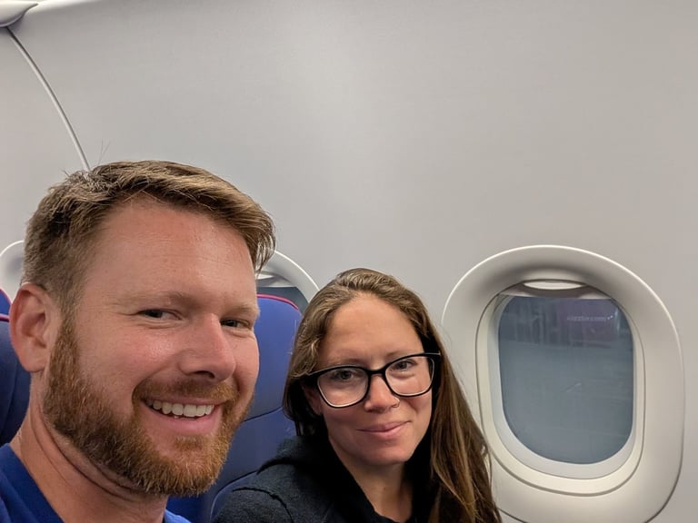 A smiling couple taking a selfie while sitting in their seats on a Wizz Air airplane flight.
