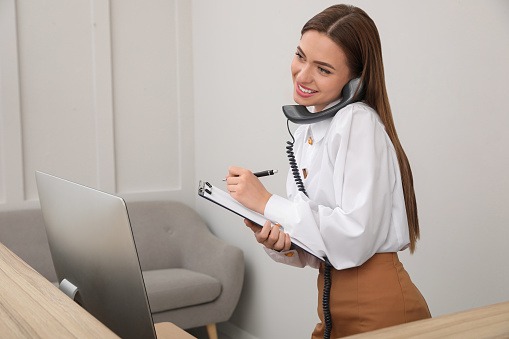 Une femme, assistante administrative au teléphone, devant son ordinateur, à l'accueil,