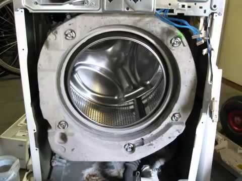 Front panel of a washer is removed for pump repair