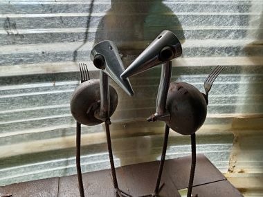 Pair of metal bird sculptures handmade from recycled scrap metal and silverware forks.