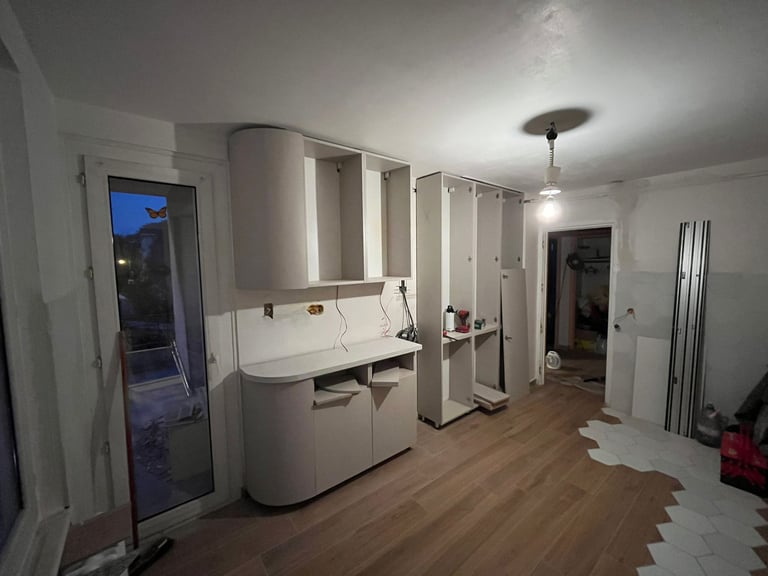 Custom kitchen cabinets being installed in a modern home renovation with wood flooring.