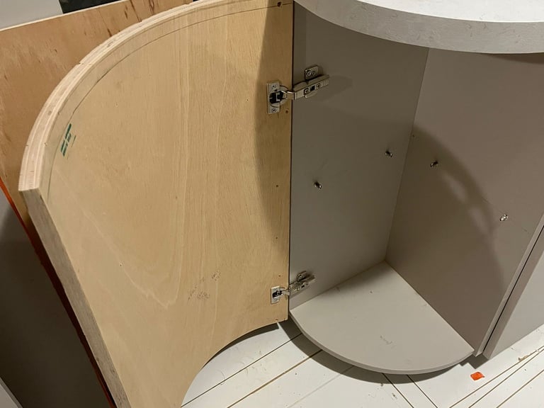 Custom curved plywood cabinet door with hidden hinges for a rounded kitchen island base.