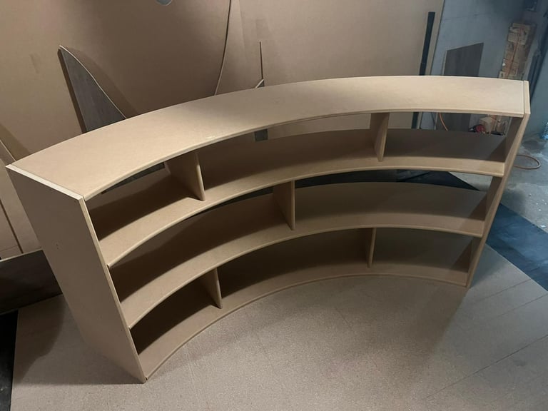 Custom curved wooden bookshelf made of MDF being assembled in a woodworking workshop.