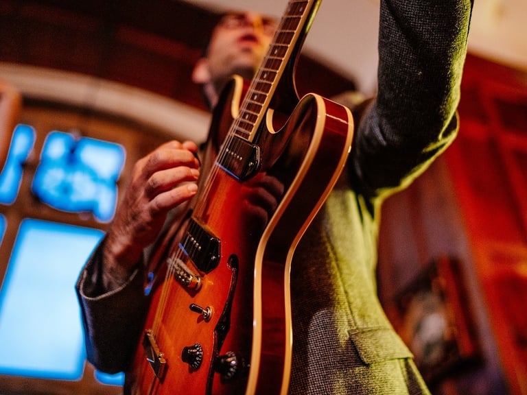 a man holding a guitar and playing a guitar