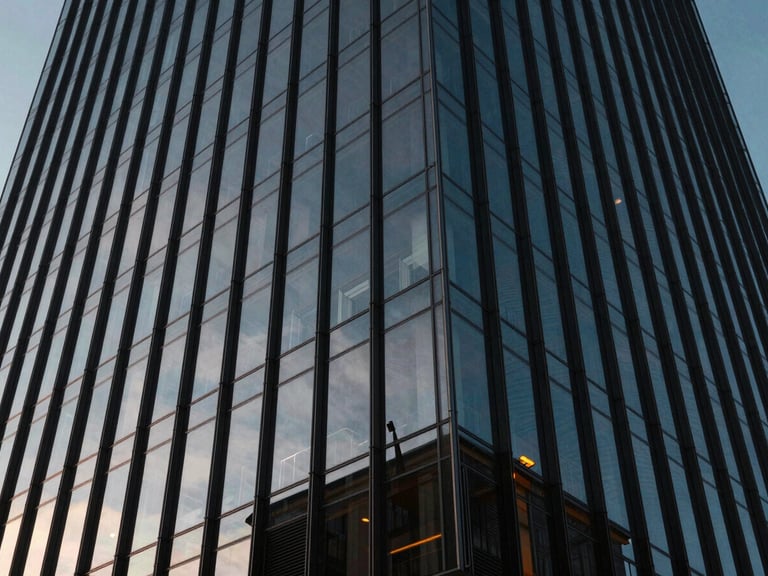 Structured glass facade of a modern skyscraper reflecting a clear sky, dramatic perspective from below, high contrast, deep navy shadows, 35mm lens.