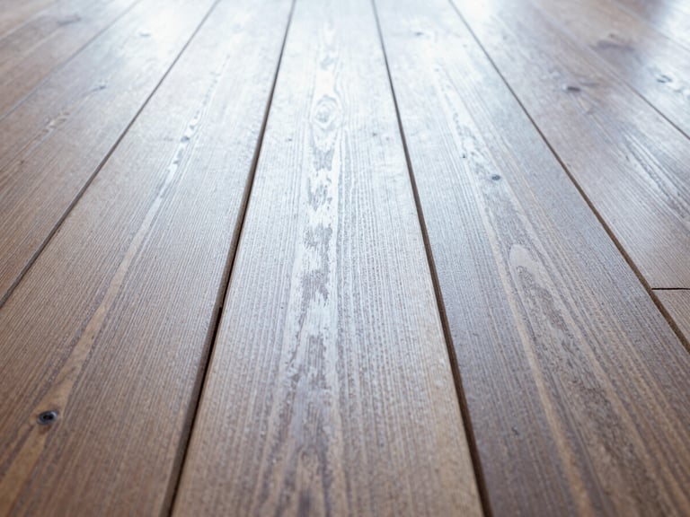Close-up of perfectly aligned hardwood planks under natural light, showcasing grain and texture, low-angle, rich wood tones.