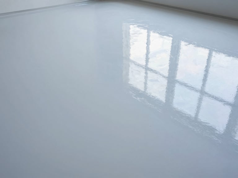High-gloss epoxy garage floor with crisp reflections, wide-angle, bright overhead lighting, cool tones, emphasizing seamless finish.