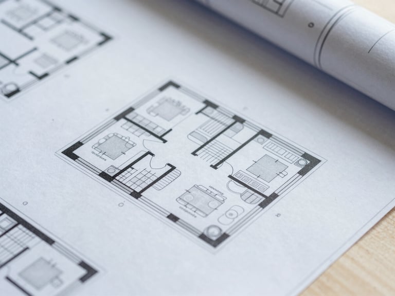 Overhead macro shot of architectural floor plans and structural drawings on a clean studio table, sharp focus, cool daylight.