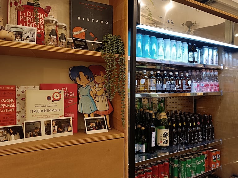 Scaffale con libri manga e frigorifero con bibite giapponesi da Maido