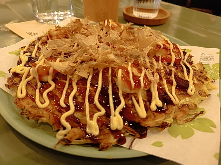 Okonomiyaki giapponese con salsa e scaglie di bonito servito da Maido