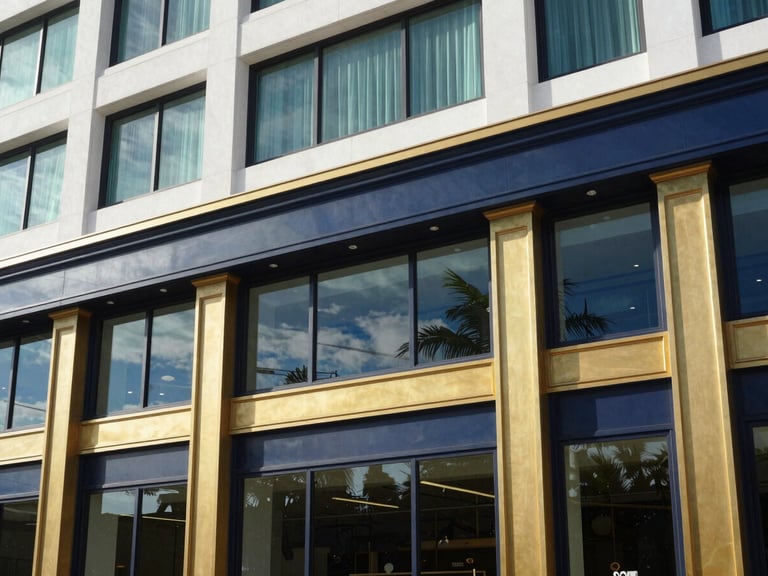 Architectural detail of a premium commercial building facade in South Florida, bright natural coastal window light, deep navy and warm gold accents, sharp focus, 35mm lens
