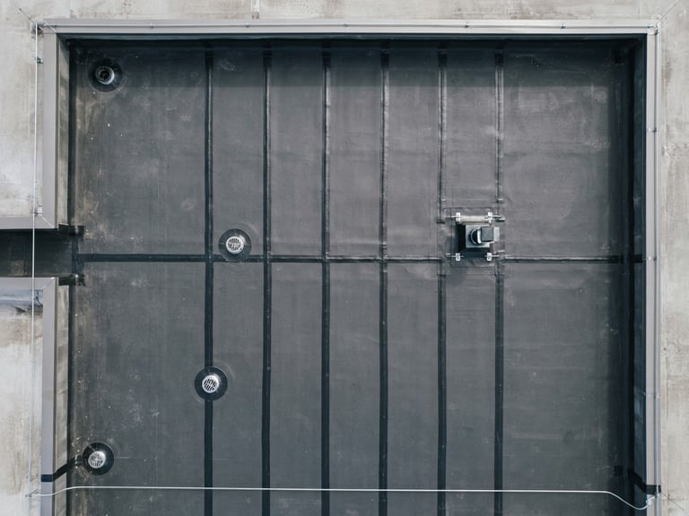 Top-down technical view of a perfectly welded black waterproofing membrane on a clean concrete flat roof, sharp lines, architectural precision, bright overcast daylight, 35mm