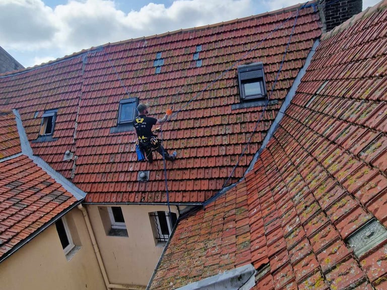 cordiste qui intervient sur une toiture en tuiles