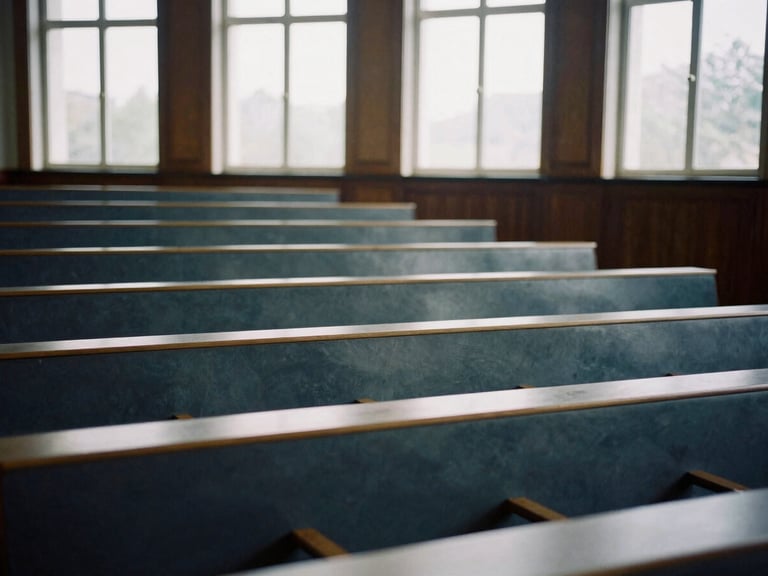 Wide environmental shot of an empty high-end lecture hall with dark wood paneling, soft natural light streaming through high windows, muted slate and navy tones, 35mm film