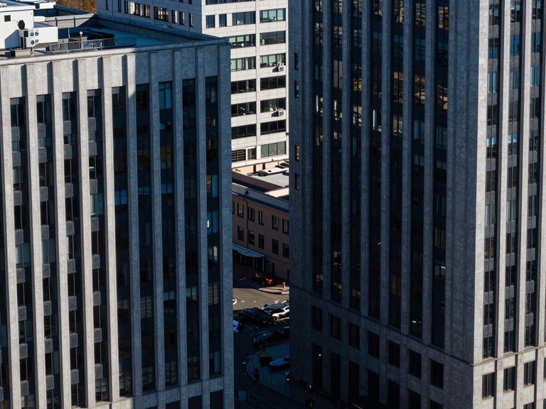 High-angle architectural lines of modern corporate offices in St. Petersburg, sharp shadows, cool high-contrast daylight, deep blue and charcoal tones, 35mm lens