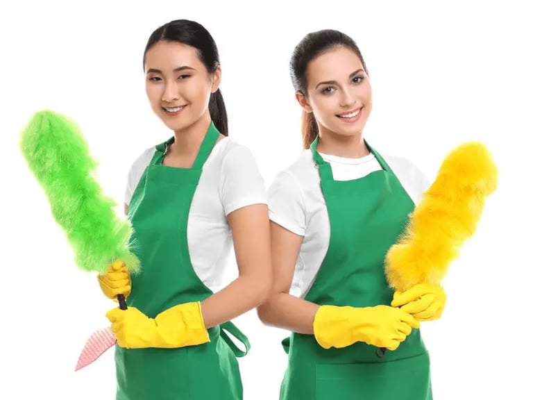 two women in green aprons holding cleaning supplies