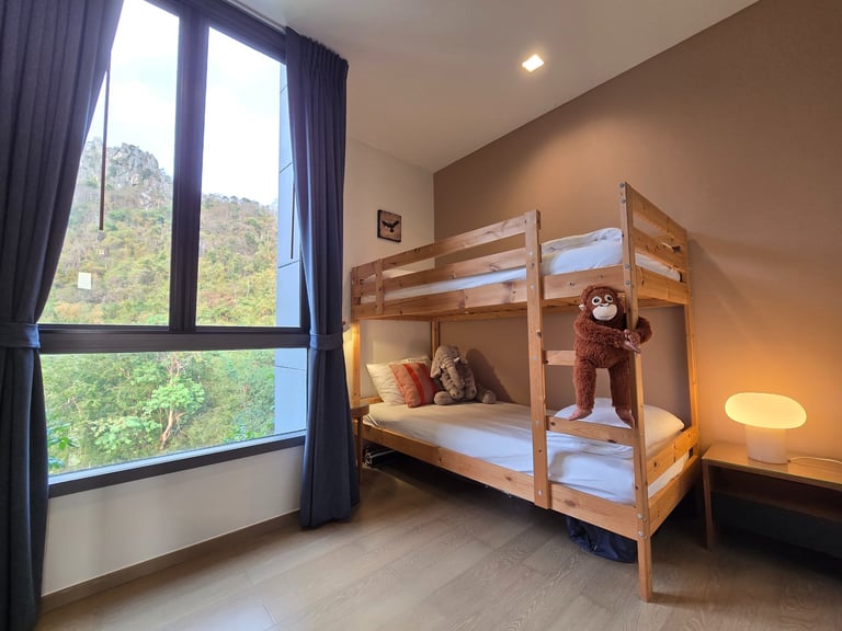 Modern wooden bunk bed in a bedroom with a scenic mountain view window and stuffed animals.