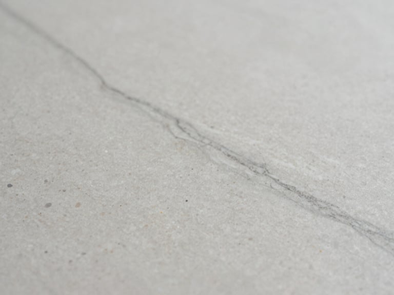 Macro detail of subtle grey veining in an engineered quartz surface, soft diffused side-light, sharp focus, 35mm lens, architectural interior photography