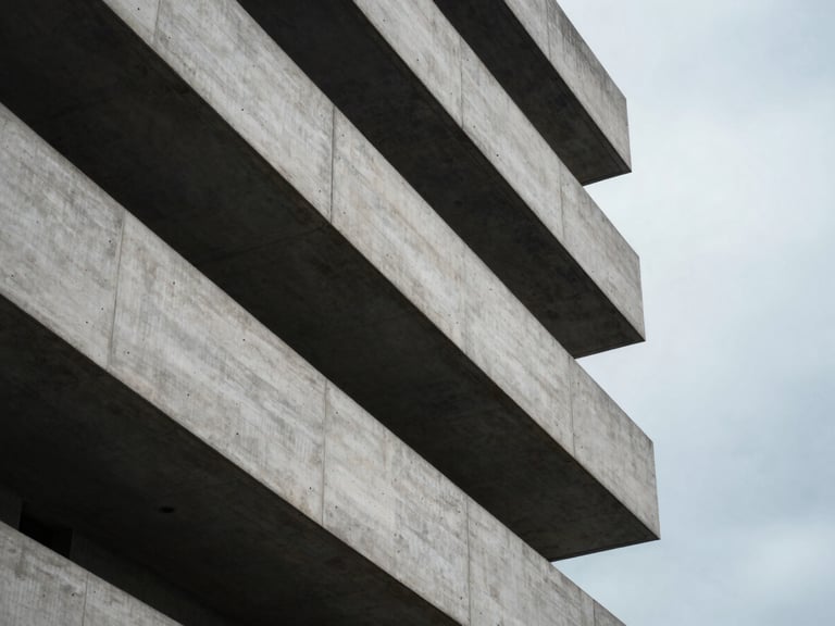 Abstract architectural lines of a concrete building under overcast skies, soft-focus composition, high negative space.