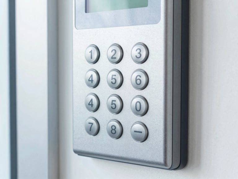 Close-up of an access control keypad with a clean metallic finish, mounted on a brushed steel frame, bright cool indoor lighting.