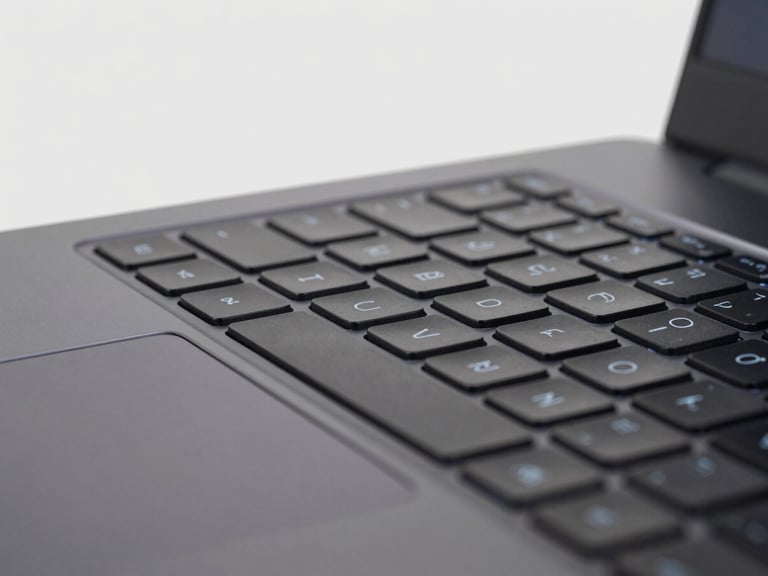 Close-up of a high-performance gaming laptop keyboard with subtle backlighting, clean studio lighting, light gray background, sharp details