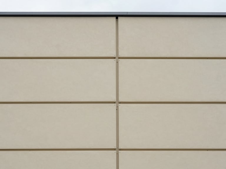 Crisp architectural photography, straight-on architectural elevation showing rigid insulation panels being fitted, natural overcast daylight, 35mm lens.