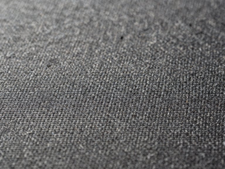 Extreme close-up of fine textile weave, individual threads visible, soft diffused light revealing texture and shadow depth, spare composition with generous negative space at left