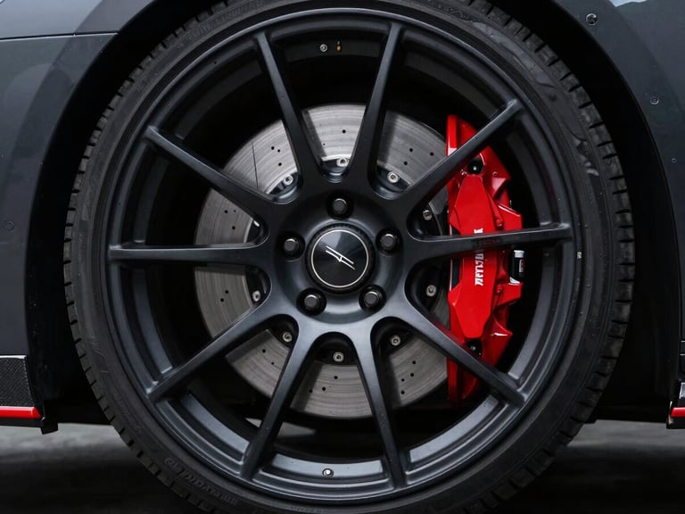 Low-angle shot of a custom black-dipped wheel and red brake caliper, dramatic studio lighting, 50mm